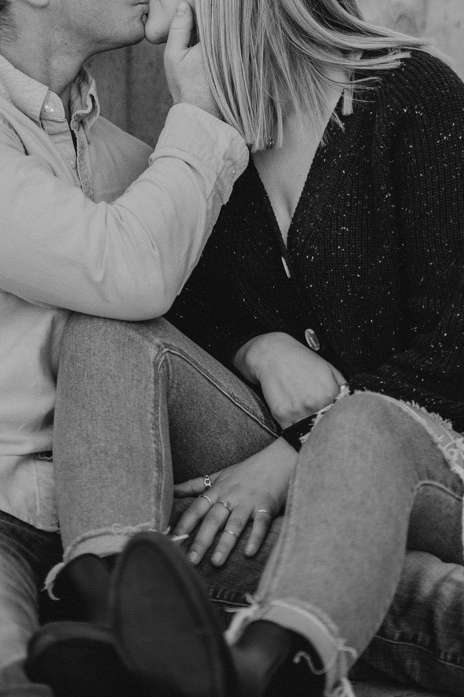 Black and white intimate moment between two people in casual clothing sitting close together.