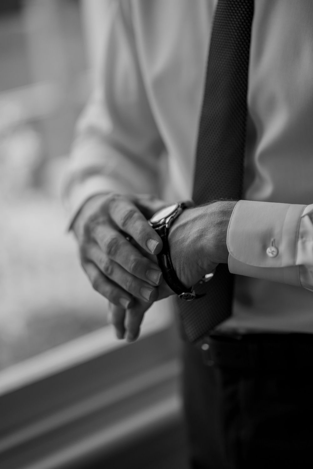 Close-up black and white detail of hands adjusting formal attire.