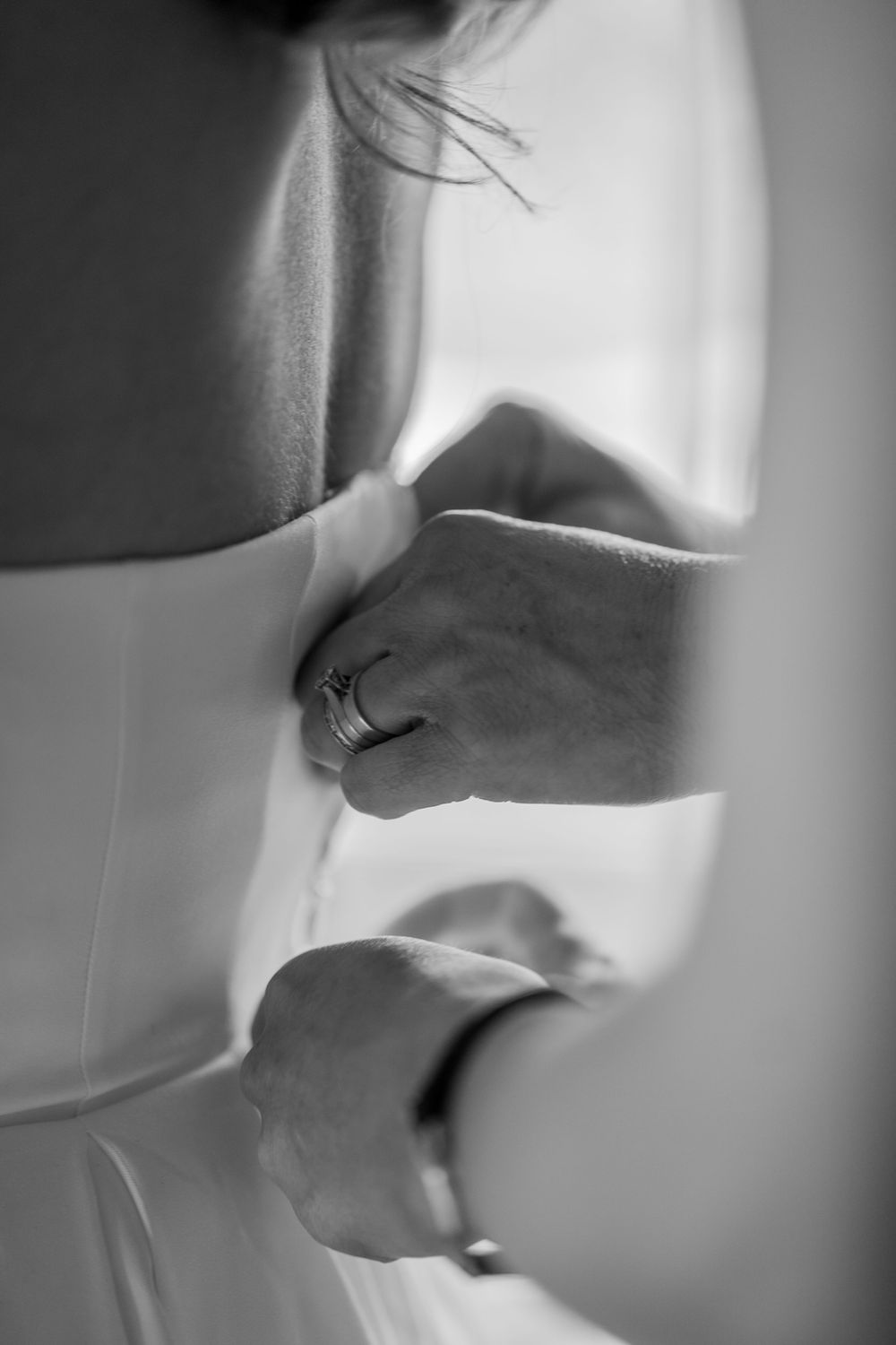 Artistic black and white photo of hands preparing wedding details.