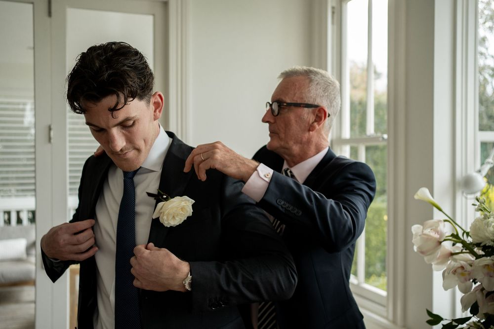 Men in formal suits adjusting their ties before an event.