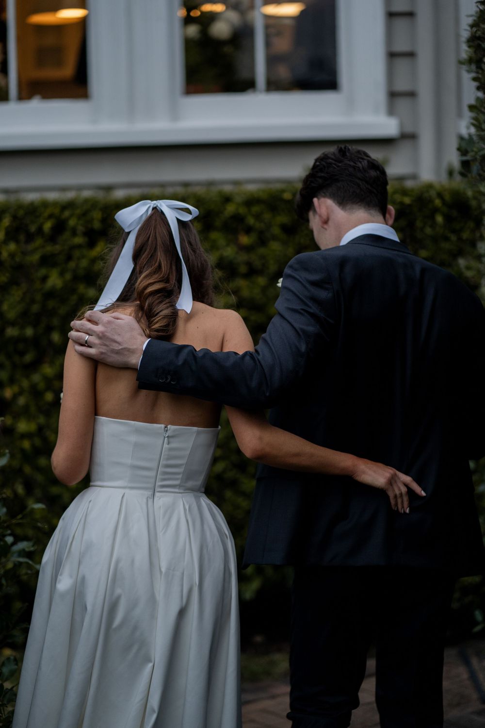A couple in formal attire embrace during a romantic evening photoshoot.