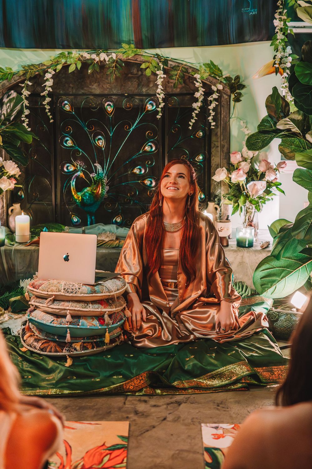 Bohemian meditation setup with laptop, candles, and tropical decor in a peaceful indoor garden setting.