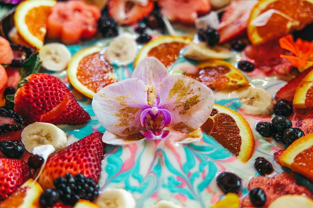 Colorful fruit platter decorated with fresh strawberries, citrus slices and an elegant orchid flower.
