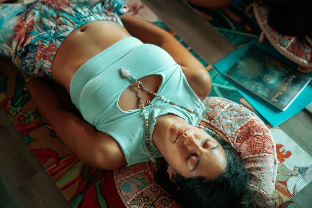 Woman in turquoise top lying down during an artistic photoshoot with dramatic lighting.
