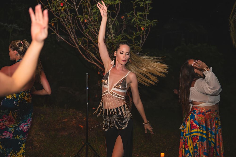 Group dancing outdoors at night with colorful dresses and flowing movements.