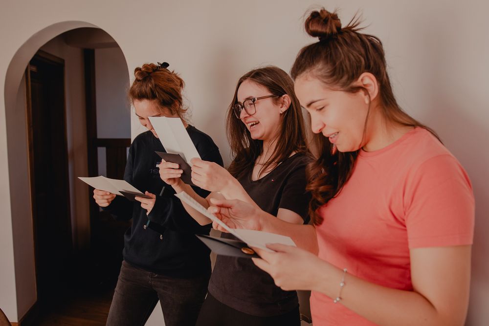 People reading from papers while standing in a hallway with an arched doorway.