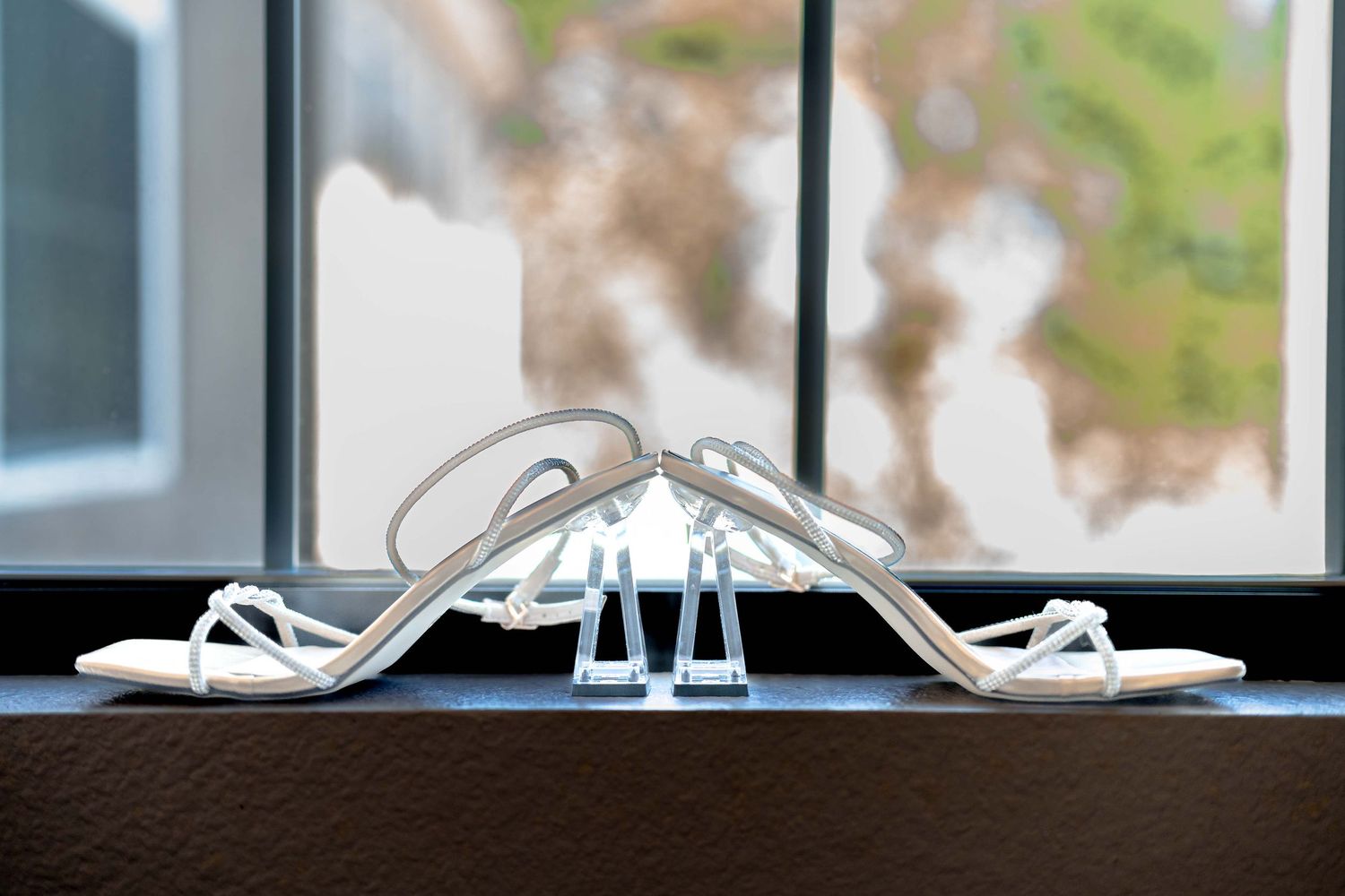 Wedding shoes and accessories arranged on windowsill with natural lighting.