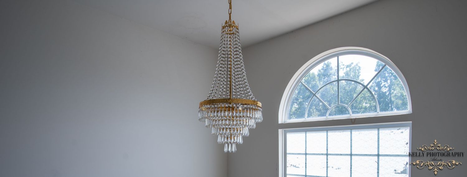 Crystal chandelier hanging beneath arched window in elegant room interior.