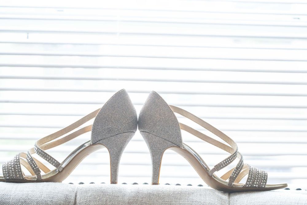 Silver and crystal bridal shoes arranged artistically against white background.
