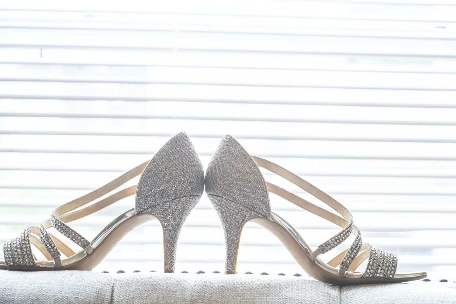 Silver and crystal bridal shoes arranged artistically against white background.