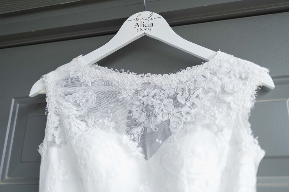 White lace wedding dress details hanging on display hangers.