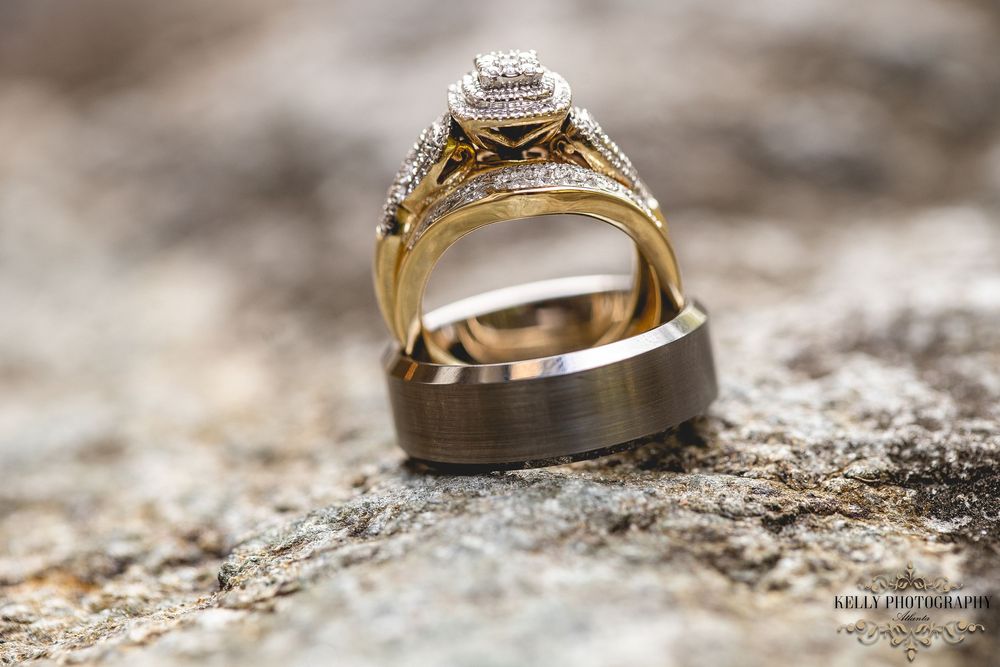 Wedding rings with diamond engagement ring displayed on textured stone surface in macro photography.