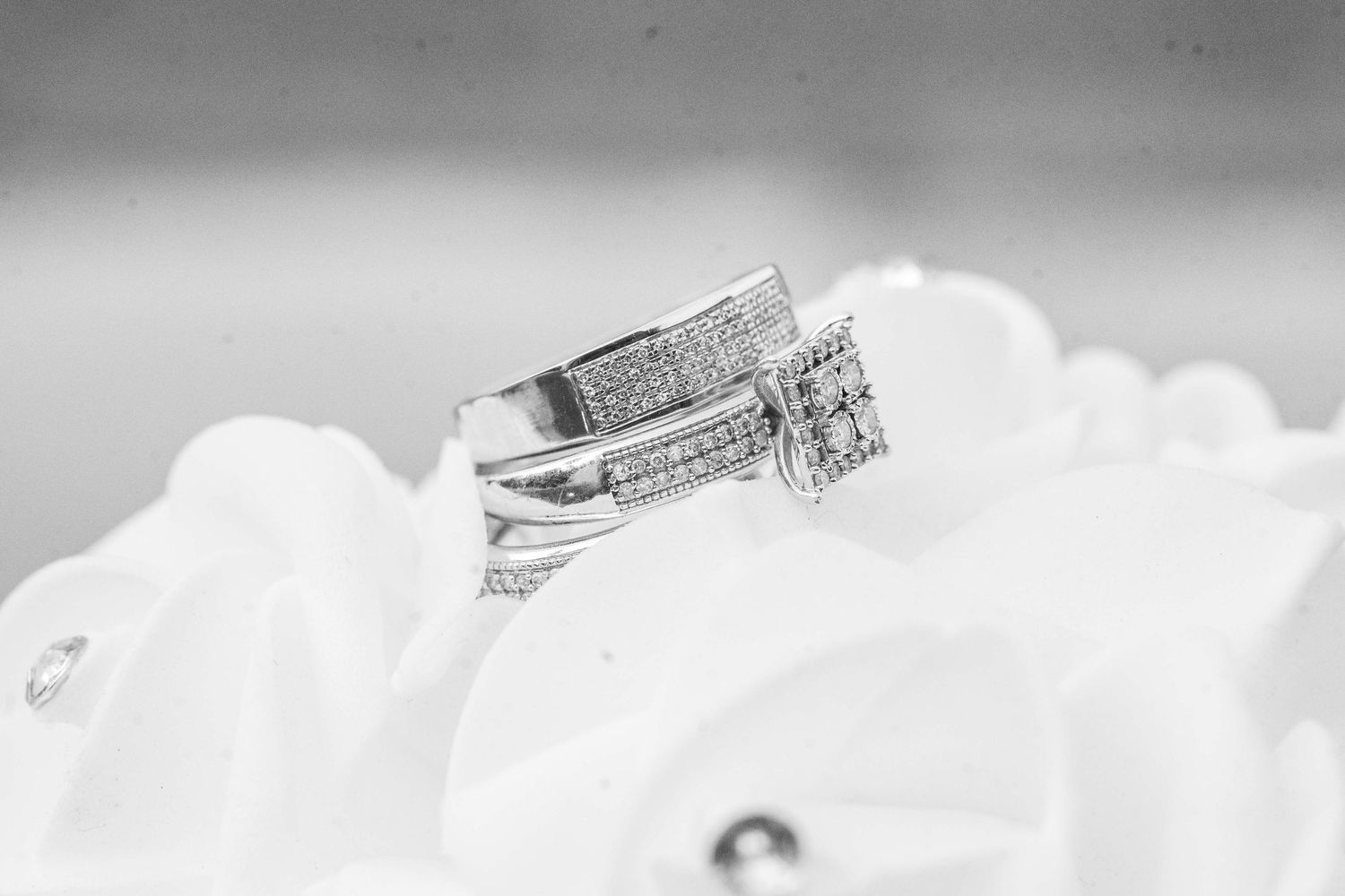 Diamond wedding rings nestled in soft white fabric with shallow depth of field.