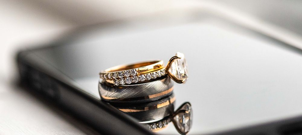 Elegant diamond engagement ring and wedding band set photographed on white surface.