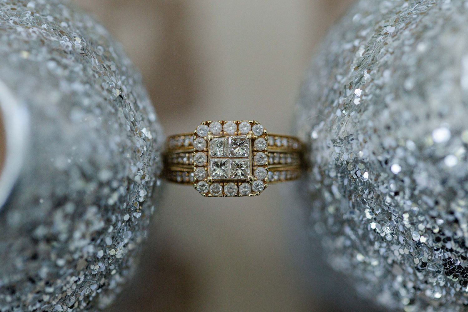 Gold diamond engagement ring with multiple stones photographed between sparkly surfaces.
