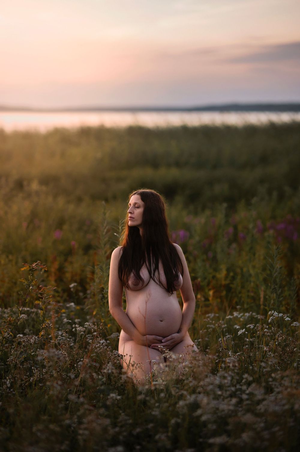 A person sits among wildflowers in a golden field at sunset, captured in a dreamy, ethereal atmosphere.