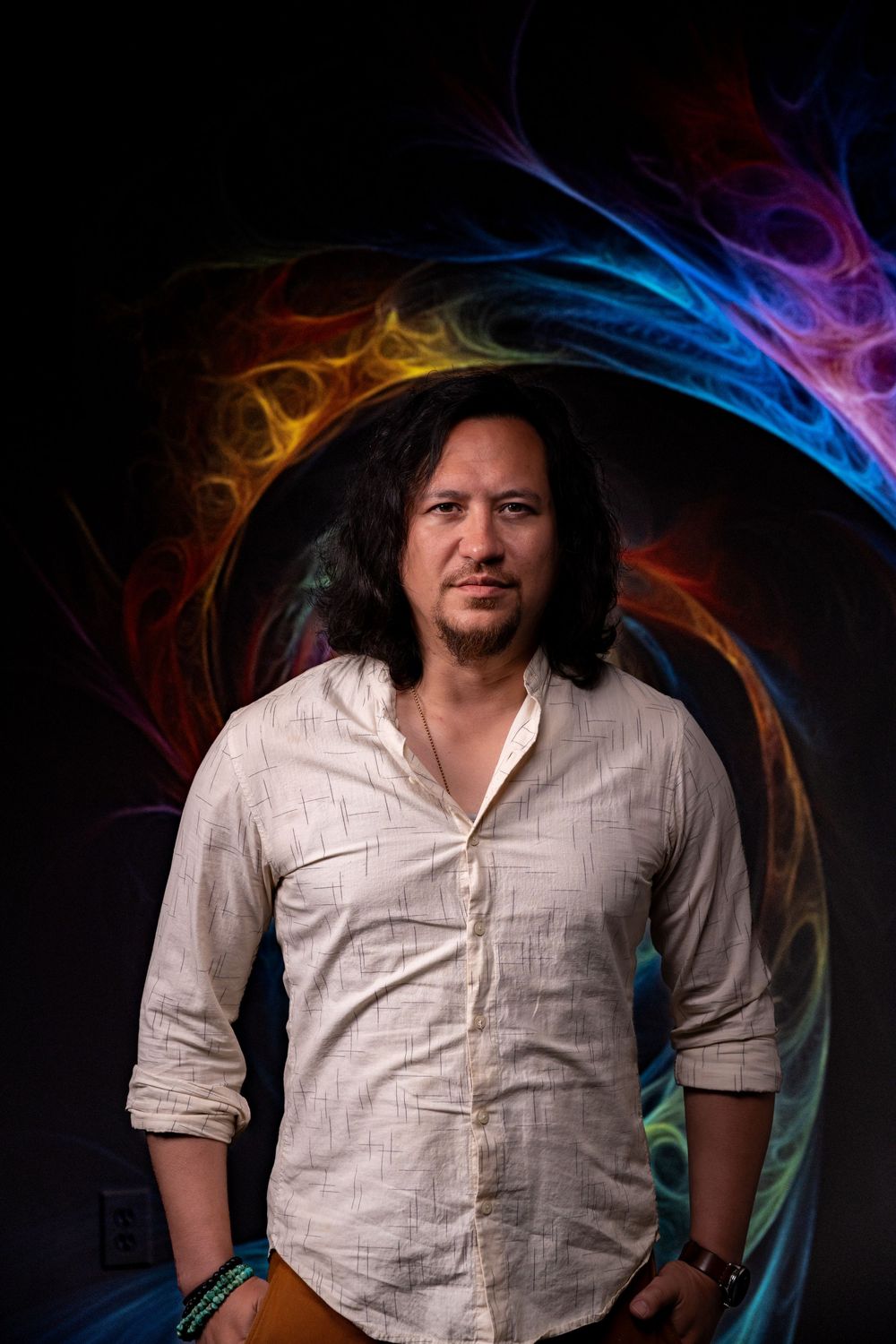Portrait against dark background with colorful rainbow smoke effects swirling around in striking artistic composition.