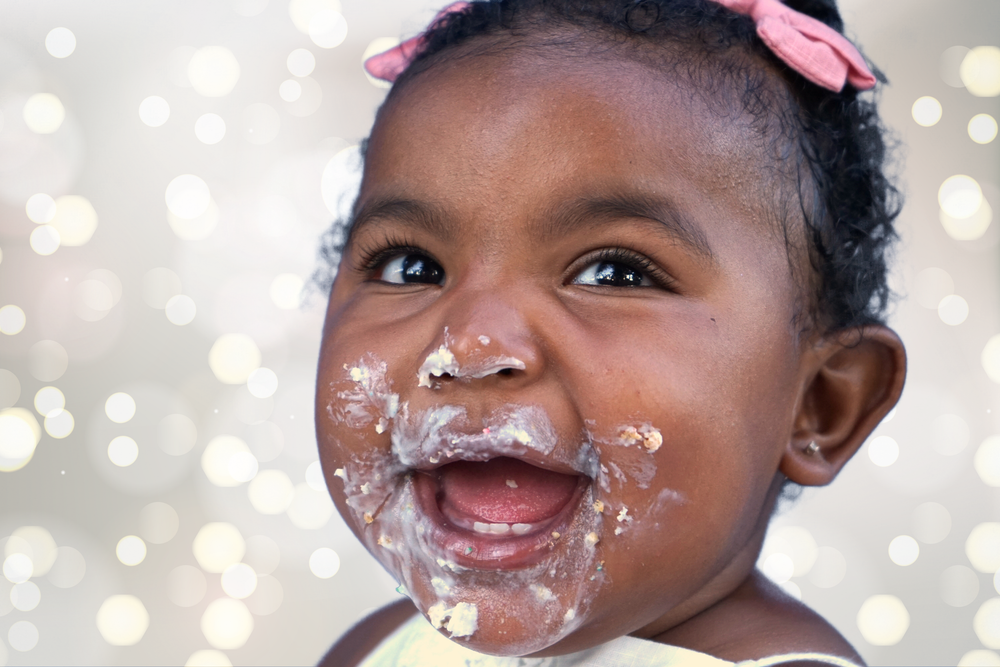 Baby with frosting on face smiling during first birthday cake smash photoshoot.