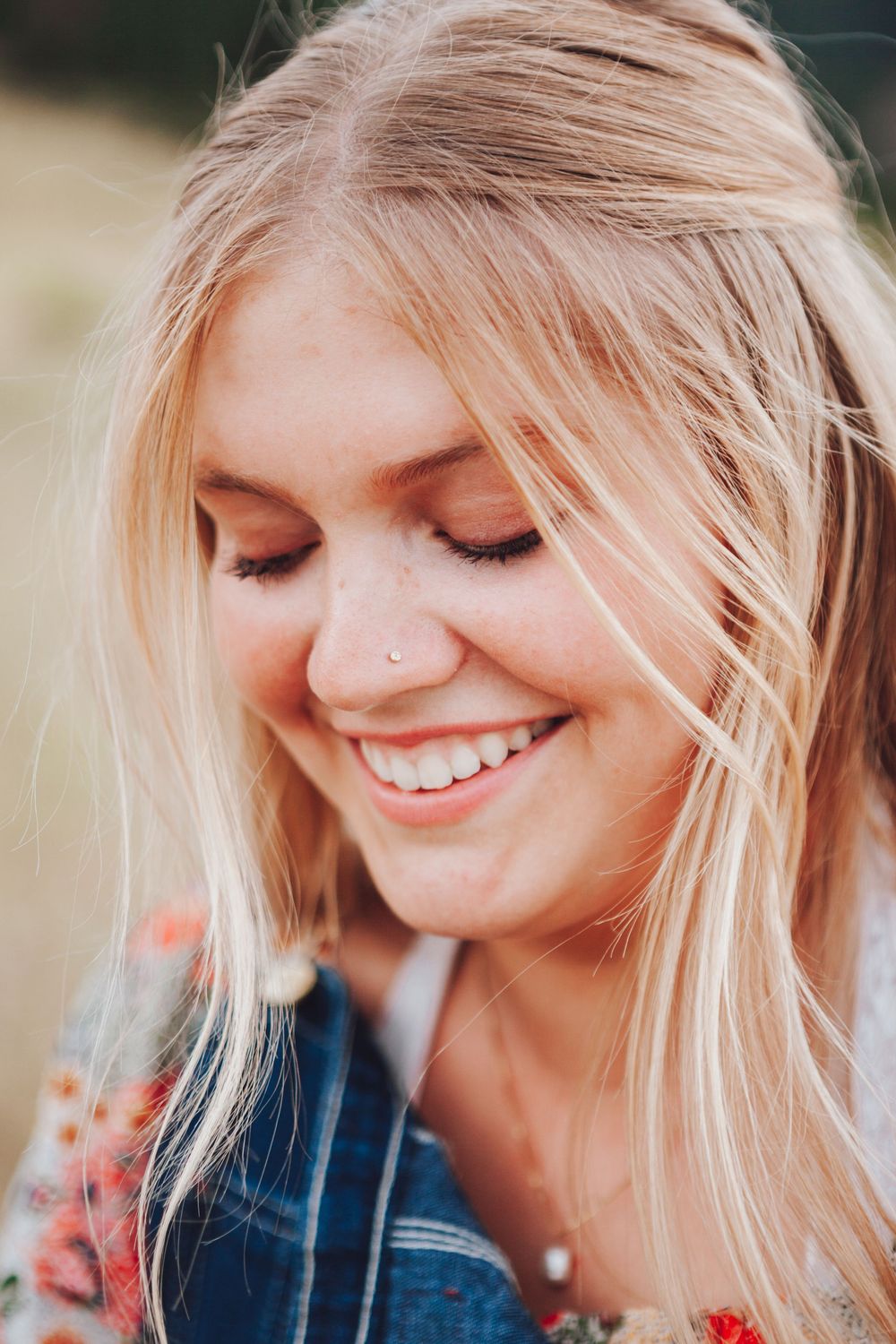 A blonde person with windswept hair smiles joyfully in a series of candid close-up profile portraits captured outdoors.