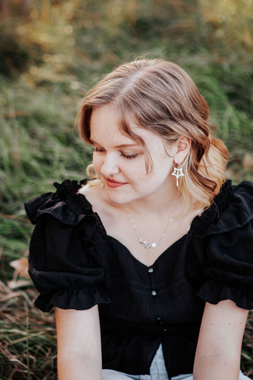 A person in a black ruffled top poses with a gentle downward gaze in a series of outdoor portrait photos.