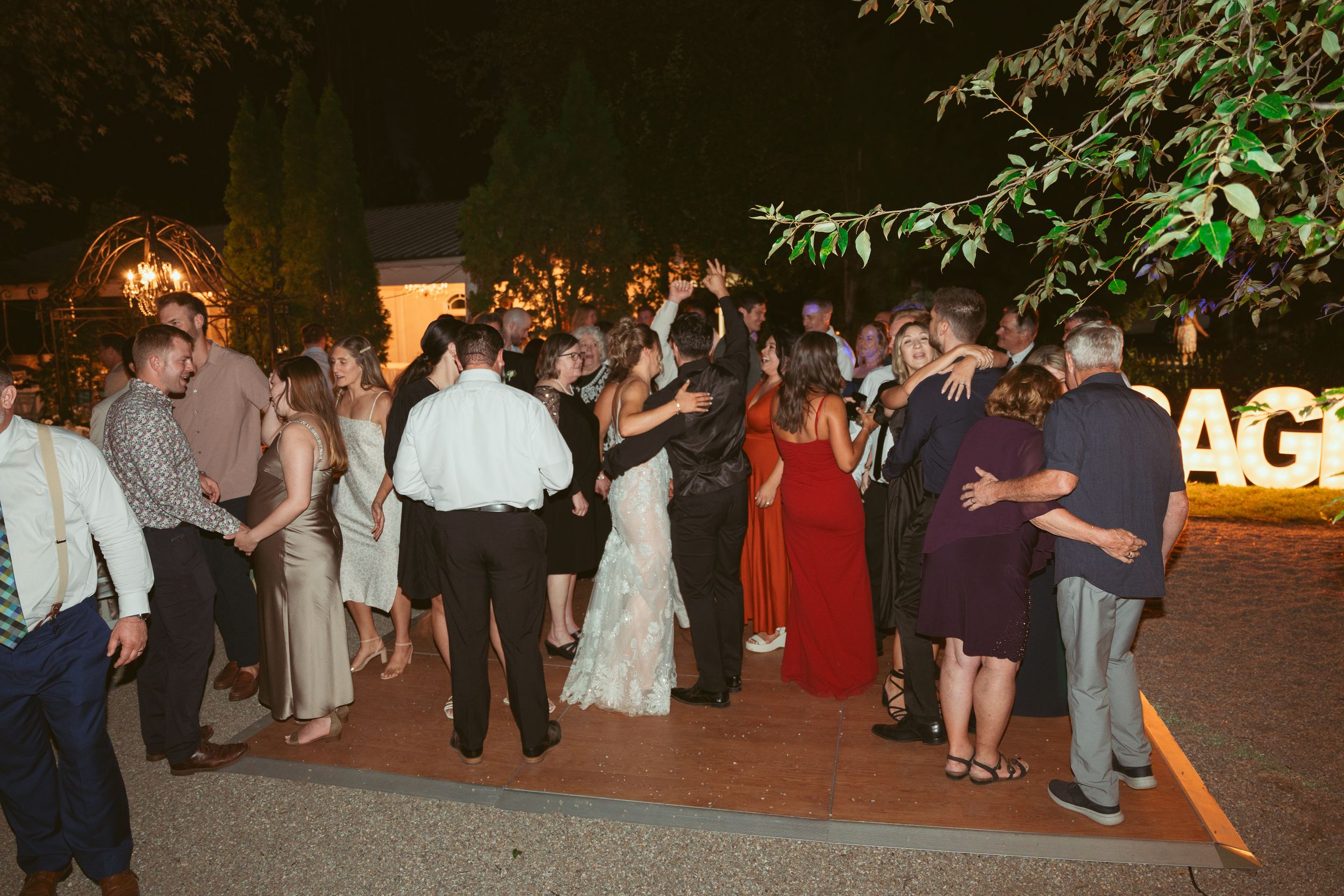 Wedding guests dancing and mingling during outdoor evening reception.