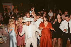 Lively dance party at outdoor wedding reception with guests in formal attire.