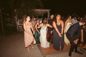 Wedding guests dancing and celebrating on outdoor reception dance floor at night.