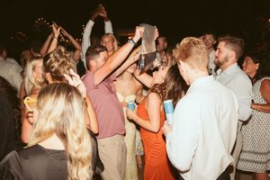 People dancing and having fun at a lively wedding reception with ambient lighting.