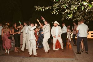 Wedding guests dancing and walking along a paved pathway during an evening reception.
