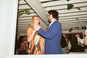 Couple shares intimate dance moment under white pergola at wedding reception.