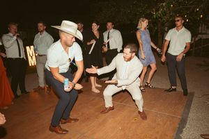 People dancing energetically on a wooden dance floor at a nighttime outdoor party event.