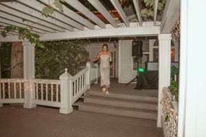 A white covered porch area decorated with string lights creating a romantic wedding venue atmosphere.