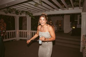 Woman in sparkly dress dances happily at wedding reception.