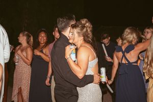 Festive couples dance together at a nighttime wedding reception while holding drinks.