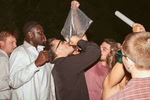 Wedding guests drinking and celebrating together during an outdoor nighttime reception.