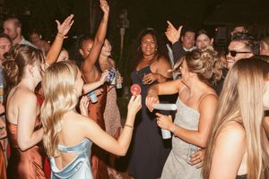 Crowded dance floor at a wedding reception with people dancing and raising their hands in celebration.