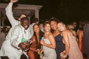 Wedding guests posing together at a lively outdoor reception celebration.