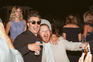 Wedding guests celebrate and laugh together at an evening outdoor reception.