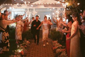 Wedding couple exits through sparkler send-off line with guests on a brick pathway.