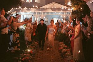 Newlyweds walk through sparkler exit tunnel as guests create magical nighttime moment.