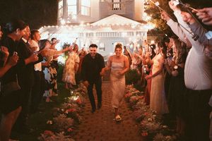 Wedding celebration under glowing lights with guests dancing outdoors.