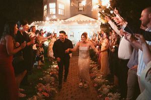 Wedding guests dancing and celebrating at a lively nighttime reception with sparklers.