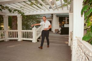 Person dancing solo on a white wooden deck porch with lattice pergola overhead.