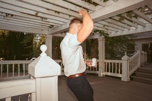 Person dancing energetically on an outdoor white wooden deck with pergola covering.