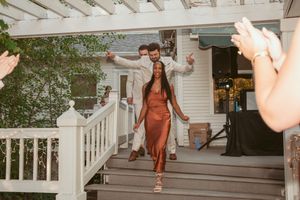 Person in rust-colored dress descends white wooden steps at outdoor venue during celebration.