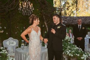 An elegant outdoor wedding reception setup with white chairs and floral arrangements under garden lights.