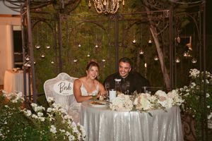 Elegant wedding reception table decorated with white flowers and chandelier lighting.