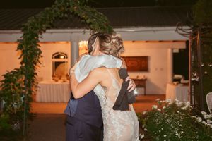 Wedding couple shares intimate moment during reception under decorative greenery and warm lighting.