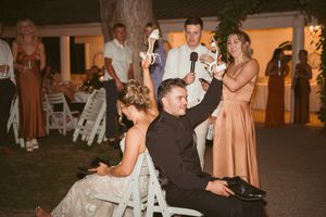 Celebratory moment at an outdoor wedding reception with guests seated on white chairs.