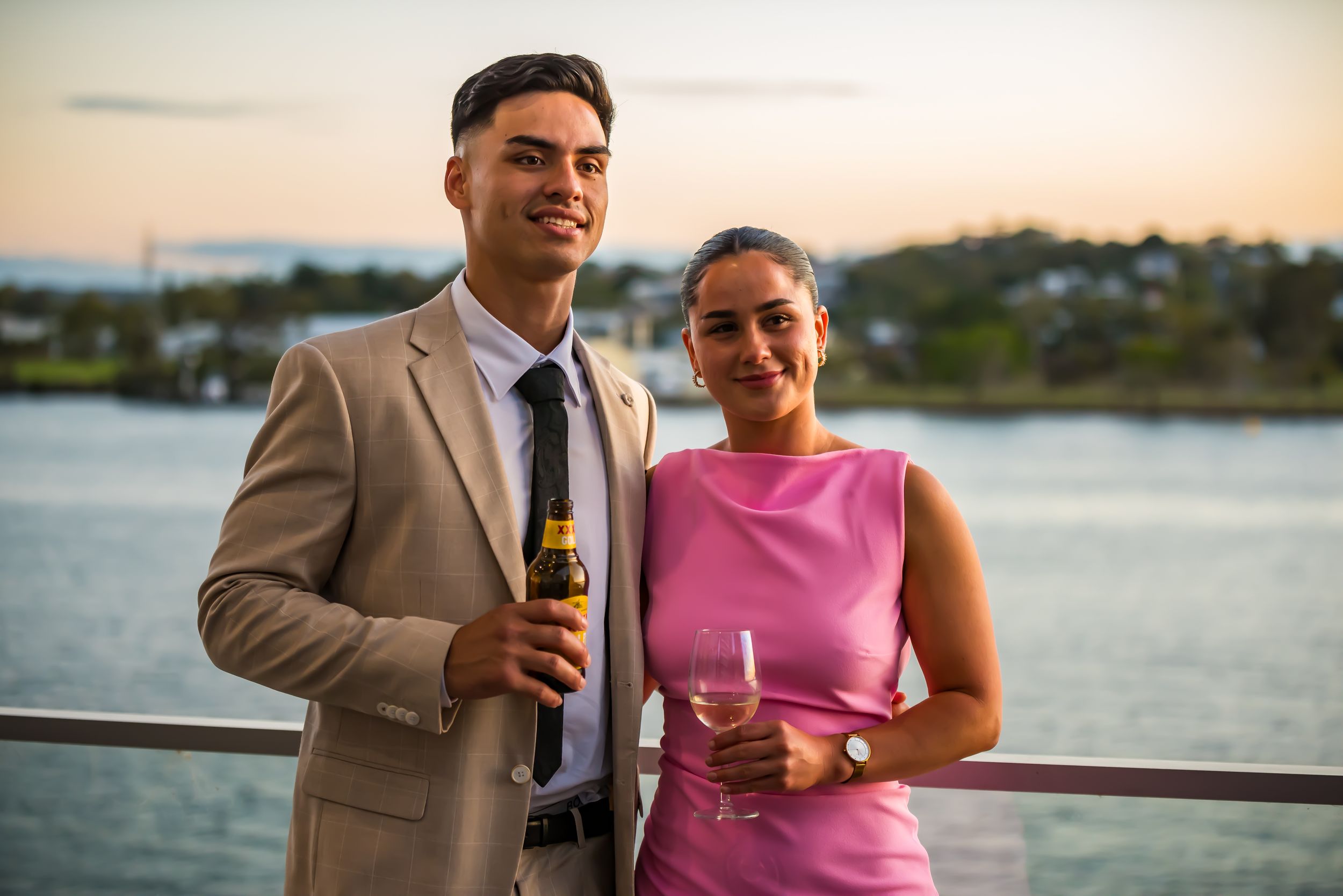 Couple enjoying drinks together on waterfront deck during sunset.